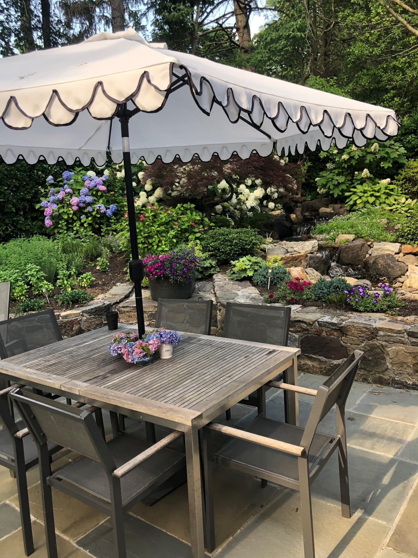 This Larchmont backyard has a serene feeling with a pond and lush plantings surrounding this bluestone patio